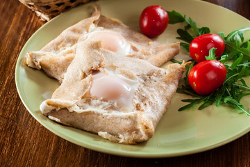 Crepes with ham, cheese and poached egg on a plate