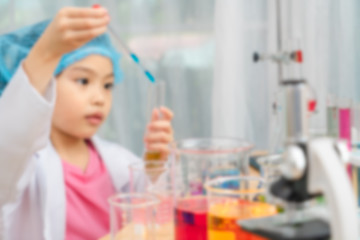 Asian little girl playing with fun as a scientist working in a lab equipped with colored glass tubes. picture is blur.