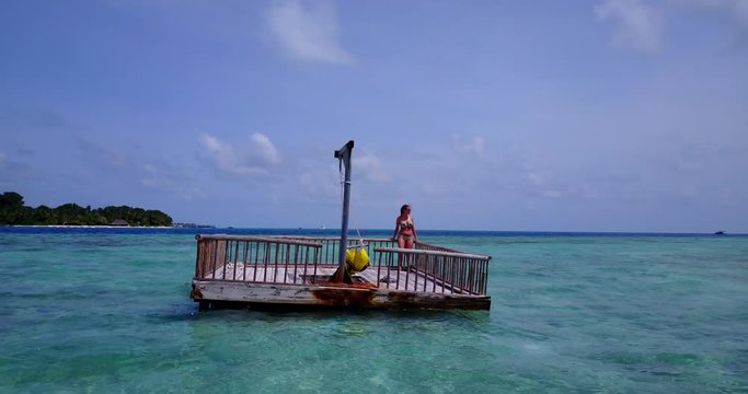 Young Woman Standing On A Wooden Raft In A Blue Lagoon And Sunbathes In The Sun, Seychelles