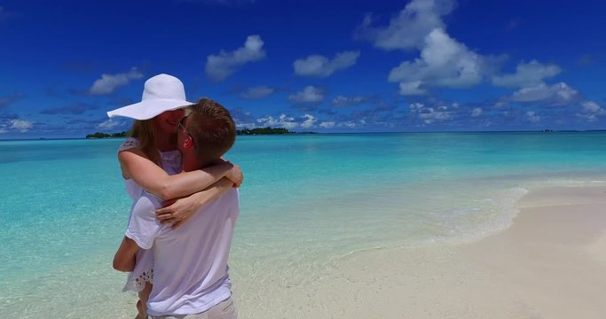 Camera circling a  happy couple in love hugging and kissing barefoot on an exotic beach in the Maldives for their honeymoon 4K