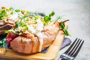 Baked sweet potatoes stuffed with quinoa, vegetables and tahini. Baked vegetables, vegan food concept.