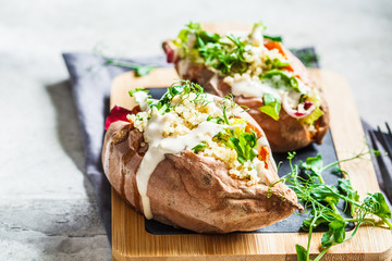 Baked sweet potatoes stuffed with quinoa, vegetables and tahini. Baked vegetables, vegan food concept.