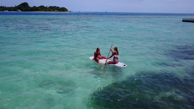 Aerial footage going around two girls on a paddle board on an exotic island in Malaysia 4K