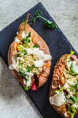 Baked sweet potatoes stuffed with quinoa, vegetables and tahini, top view. Baked vegetables, vegan food concept.