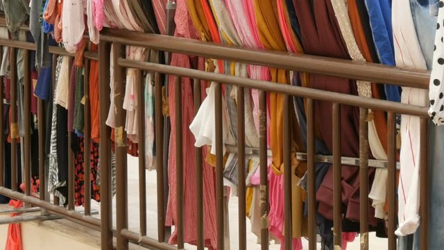 Row of various women's clothes hanging on hangers in clothing store