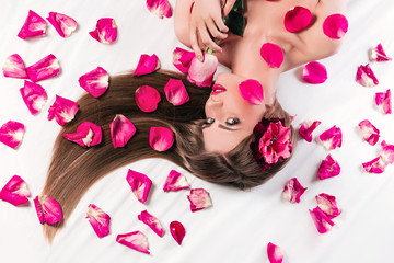 Obraz na płótnie Canvas beautiful fashionable girl lying among rose petals