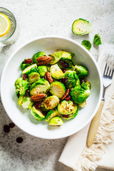 Roasted Brussels sprouts salad with cranberries and nuts in white bowl, top view. Healthy vegan food concept.