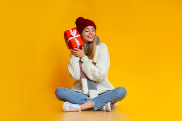 Peaceful woman sitting on floor and holding gift