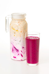 Jug of sweet colorful layered yougurt with fruits and berries and a glass of dragon fruit juice at white background. Concept of detox and vegan healthy lifestyle.