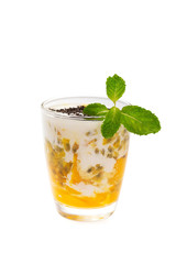 Closeup glass of healthy tropical fruit smoothie with mango, passion fruitc coconut milk and chia seeds decorated with mint isolated at white background.