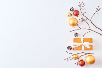 Flat lay border with gold christmas balls, branches and gift box on a white background