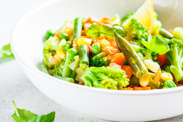 Steamed vegetables (broccoli, carrots, beans, peas, corn) in white plate. Healthy diet food concept.