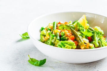 Steamed vegetables (broccoli, carrots, beans, peas, corn) in white plate. Healthy diet food concept.