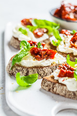 Sandwiches with cottage cheese and sun-dried tomatoes on white board.