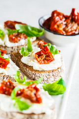 Sandwiches with cottage cheese and sun-dried tomatoes on white board.