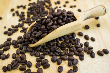 Coffee bean and wooden scoop on natural wood table with great texture and ambiance background for menu or cafe