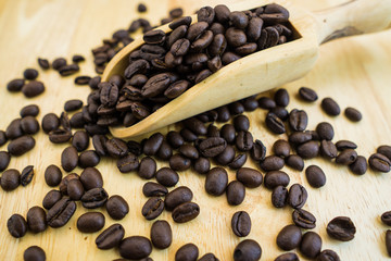 Coffee bean and wooden scoop on natural wood table with great texture and ambiance background for menu or cafe