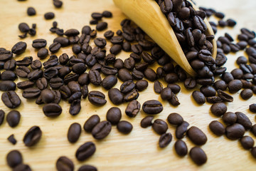 Coffee bean and wooden scoop on natural wood table with great texture and ambiance background for menu or cafe