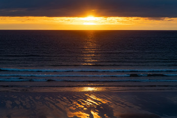 Fototapeta na wymiar Golden sunset reflections on the sea at Cornwall