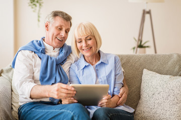 Surfing internet. Mature couple using digital tablet