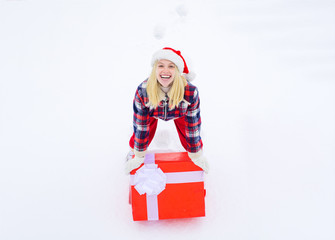 Delivery girl with winter gift box. Winter fun activities. Winter emotion. Crazy Christmas girl pushes a big gift on snow winter background.