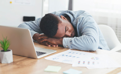 Fototapeta na wymiar Overworked african american employee sleeping at workplace in office