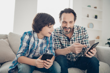 Sms message modern technology digital world generation concept. Photo of mature bearded excited guy showing new social page site shop with electronic toys to his younger son sitting on divan