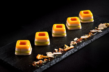 Colored marmalade, laid out in a beautiful line on a black plate. food background. Fusion food concept, low key, copy space.