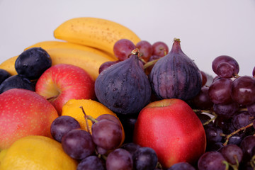 beautiful fruits, apples, plums, lemons, bananas, purple figs, clusters of black and green grapes with drops, splashes of water, close-up, vitamins concept, vegan food, healthy eating, copy space