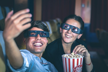 Obraz premium Couple taking a selfie in a cinema wearing 3d glasses.
