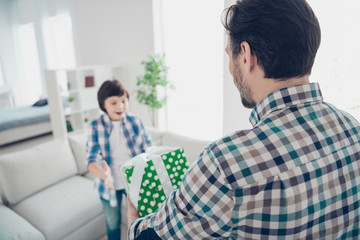 Fototapeta na wymiar Rear back behind view portrait of two nice attractive cheerful cheery glad guys dad daddy giving gift purchase box to pre-teen son event in light white modern interior house living-room indoors