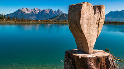 Beautiful alpine view with a heart carved from a tree stump and reflections in a lake at...
