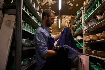 Talented young cobbler is comparing two types of fabric for new pair of shoes.