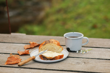 Scythe with poppy seeds, butter and tea. Baking with poppy seeds and coffee. The work of a baker. Poppy seed baking and pies.Bakery, cook together. Bun with butter on the nature in the forest. Picnic