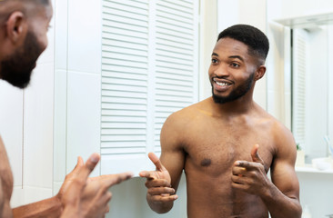 Confident african man smiling to himself at mirror reflection