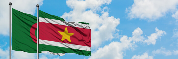 Algeria and Suriname flag waving in the wind against white cloudy blue sky together. Diplomacy concept, international relations.
