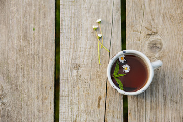 Cup with hot tea on a wooden table. Background, texture on nature. Chamomile tea. Herbal drink. Healthy Mint Drink