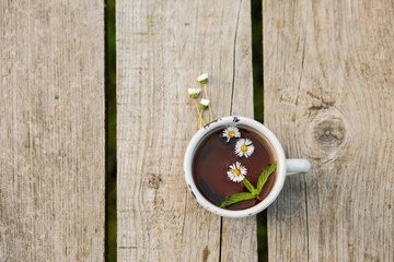 Cup with hot tea on a wooden table. Background, texture on nature. Chamomile tea. Herbal drink. Healthy Mint Drink