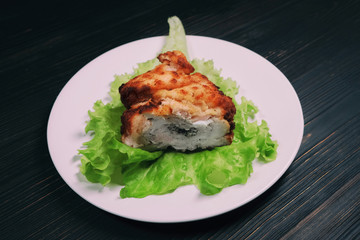 Meat cutlet with stuffing on a lettuce leaf. Plate on a dark wooden background.