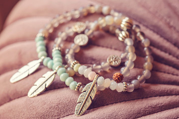 Metal feather pendant mineral faceted stone bead bracelets on pink velvet background