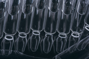 Glass medical ampoule vial for injection. Medicine is liquid sodium chloride with of aqueous solution in ampulla. Close up. Bottles ampule multicolor.
