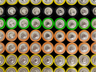 A large number of old AA batteries of different colors. Top view of alkaline batteries.