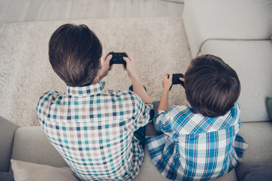 Top above high angle view portrait of two nice guys dad and pre-teen son sitting on sofa enjoying playing video game spending spare time in living-room