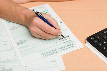close up of tax forms for last year tax declaration and hand with a pen