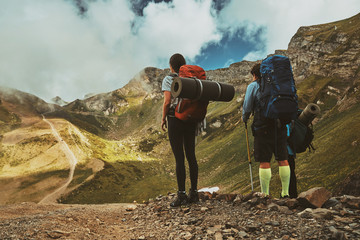 Group of hiker with heavy backpacks stands on top of a mountain and enjoying camping valley view