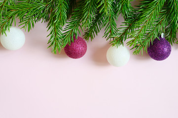 christmas tree branches with christmas decorations toys balls, frame on a pink background. space for text