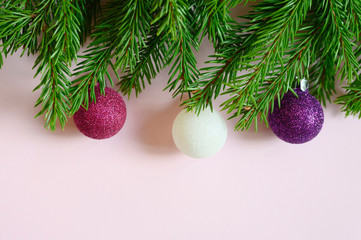 Obraz na płótnie Canvas christmas tree branches with christmas decorations toys balls, frame on a pink background. space for text