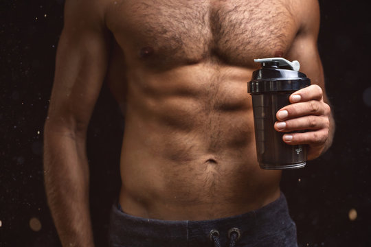 Shirtless torso of a muscular man with a shaker in one hand