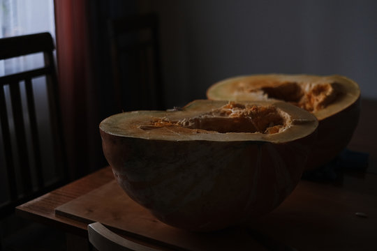 Halved Pumpkin with Seeds on Rustic Wooden Table in Low Light