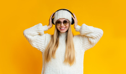 Pretty young woman in wireless headphones listening to music